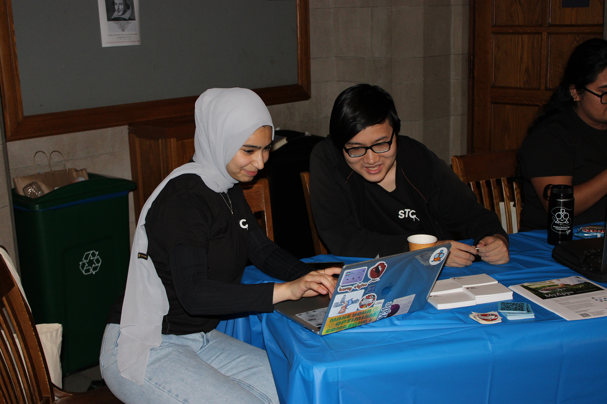 Two students sitting at a desk, looking at one computer